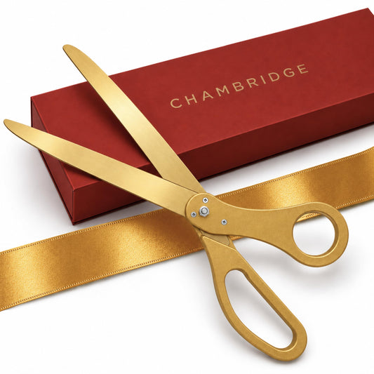 25-inch gold ceremonial scissors with gold satin ribbon, laid across a red Chambridge gift box on a white background
