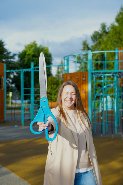 Customer smiling and holding Chambridge 25-inch blue ceremonial scissors at an outdoor grand opening