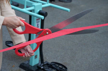 Close-up of a customer cutting the ribbon with Chambridge 25-inch red ceremonial scissors at their grand opening